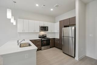 Contemporary kitchen with white and wood tone cabinetry at Cantarra Apartments, Texas