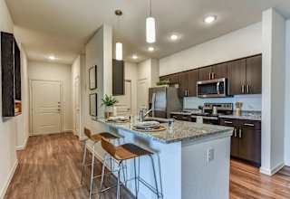 Open concept kitchen with island seating and pendant lights at High Point Preserve Apartments, Texas