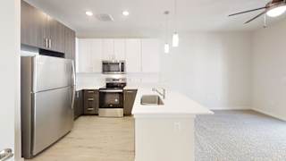 A modern kitchen with a stainless steel refrigerator and a white countertop. at Bridge at Speyside Apartments, Austin