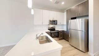 A modern kitchen with a stainless steel refrigerator and a sink with a faucet. at Bridge at Speyside Apartments, Austin, TX, 78754