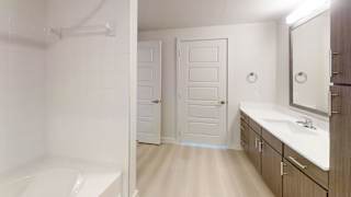 A white bathroom with a tub, sink, and mirror.