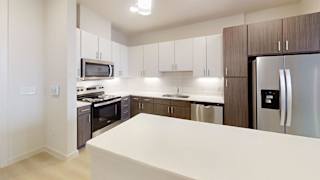 A kitchen with a white counter top and stainless steel appliances.
