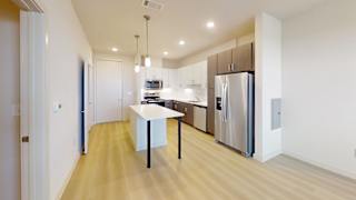 A kitchen with a white table and a stainless steel refrigerator.