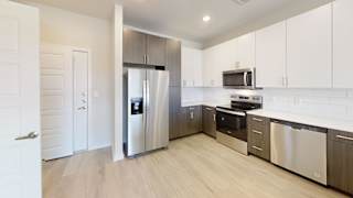 a modern kitchen with stainless steel appliances and white cabinets at Bridge at Speyside Apartments, Austin, TX, 78754