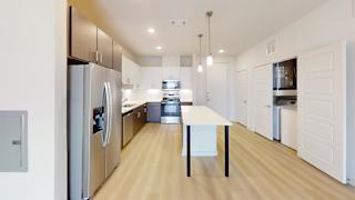 A modern kitchen with a refrigerator, oven, and a table.