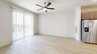 A spacious kitchen with a stainless steel refrigerator and wooden flooring.