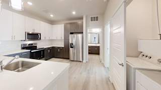 A modern kitchen with white cabinets and a stainless steel refrigerator. at Bridge at Speyside Apartments, Austin, TX, 78754