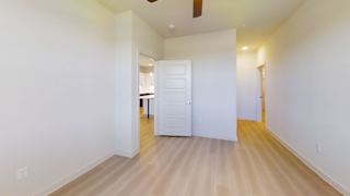 A room with a white door and a ceiling fan.