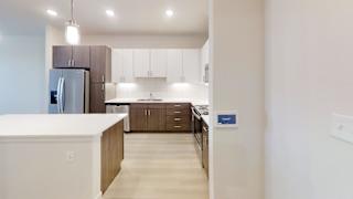 A kitchen with a refrigerator, cabinets, and a counter.
