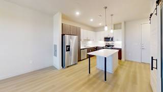 A kitchen with a refrigerator, sink, and cabinets.