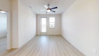 A room with a ceiling fan and a door leading to a balcony.