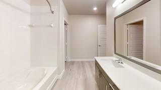 a bathroom with a sink and a bath tub and a mirror at Bridge at Speyside Apartments, Austin, TX, 78754