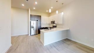 a kitchen with white cabinets and a large island with a stainless steel refrigerator at Bridge at Speyside Apartments, Texas