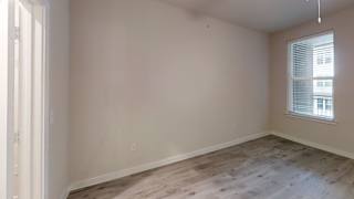 Empty bedroom with wood flooring and window at Bridge at Windsor Park Apartments, Austin, TX 78723