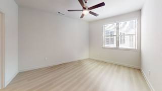 A room with a ceiling fan and a window with blinds.