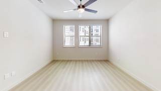 A room with a ceiling fan and a window with blinds.