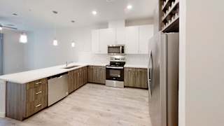 Modern kitchen with white cabinets and wood accents at Bridge at Windsor Park Apartments, Texas