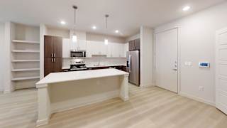 A kitchen with a white island and wooden floors.