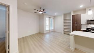 A spacious room with a ceiling fan and a kitchenette.