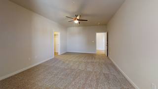 a spacious living room with carpet and a ceiling fan at Bridge at Speyside Apartments, Texas