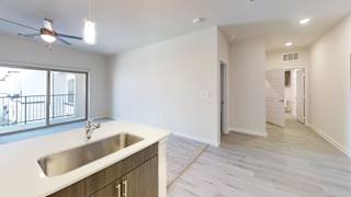 an empty kitchen with a sink and a hallway with a door to a staircase at Bridge at Speyside Apartments, Texas, 78754