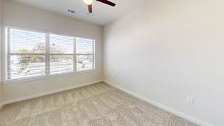 an empty bedroom with a large window and carpeted flooring at Bridge at Speyside Apartments, Austin, 78754