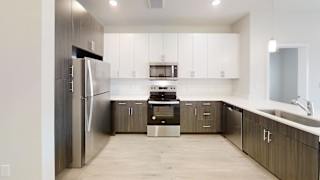 a modern kitchen with white cabinets and stainless steel appliances at Bridge at Speyside Apartments, Austin, TX, 78754