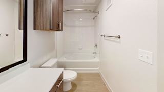 A white toilet sits next to a white sink in a small bathroom. at ThreeTwenty at the Vybe Apartments, Kyle