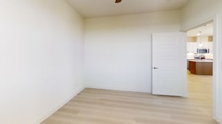 A white door is in a room with white walls and wood flooring.