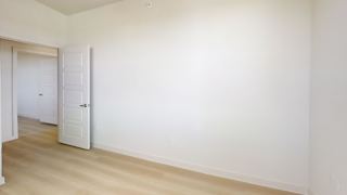 A white room with a door and a wooden floor.
