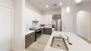 A modern kitchen with a stainless steel sink and dark wood cabinets. at Bridge at Speyside Apartments, Austin