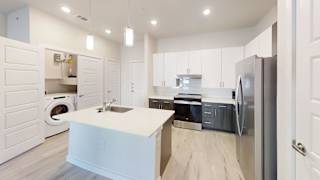 A modern kitchen with white cabinets and a central island. at Bridge at Speyside Apartments, Austin, 78754