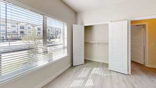 A room with a large window covered with blinds, a white door, and a wooden floor. at Bridge at Speyside Apartments, Austin, TX, 78754