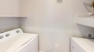A white washing machine sits next to a white sink. at Bridge at Speyside Apartments, Austin, Texas
