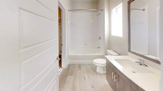 A white bathroom with a toilet, sink, and bathtub. at Bridge at Speyside Apartments, Austin