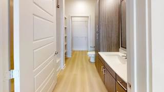 A long hallway with a toilet and sink at the end.