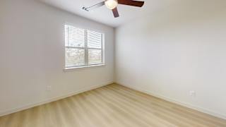 A room with a ceiling fan and a window with blinds.