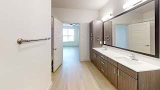 A bathroom with a white sink and a mirror. at ThreeTwenty at the Vybe Apartments, Kyle, Texas
