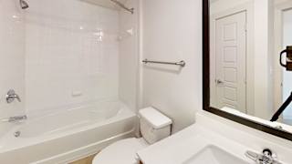 A white bathroom with a toilet, sink, and bathtub. at ThreeTwenty at the Vybe Apartments, Kyle, TX