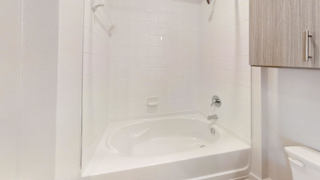 A white bathroom with a tub and toilet. at Park South Apartments, Austin