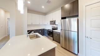 A modern kitchen with a stainless steel refrigerator and a white countertop. at Bridge at Speyside Apartments, Austin, Texas
