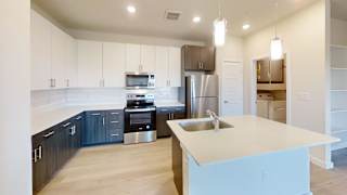 A kitchen with a white island and stainless steel appliances. at Bridge at Speyside Apartments, Austin