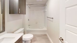 A white toilet sits next to a white sink in a bathroom. at Bridge at Speyside Apartments, Austin, TX, 78754
