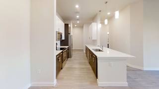 a long kitchen with white counter tops and wooden flooring and a long hallway at Bridge at Speyside Apartments, Austin, 78754