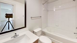 A bathroom with a white toilet, sink, and bathtub. at ThreeTwenty at the Vybe Apartments, Kyle, 78640