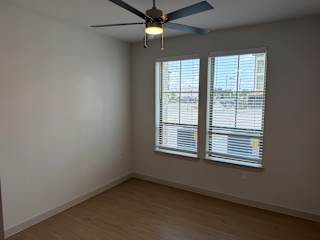 A room with a ceiling fan and two windows with blinds.