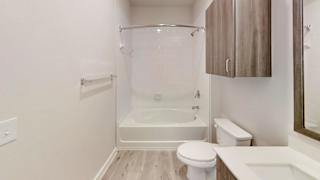 White bathtub with tiled surround and overhead cabinet at Bridge at Windsor Park Apartments, Austin, TX