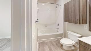 Bathroom with tub shower combo and wood grain cabinetry at Bridge at Windsor Park Apartments, Austin, 78723