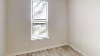 Corner bedroom with window and wood style floors at Bridge at Windsor Park Apartments, Austin, Texas
