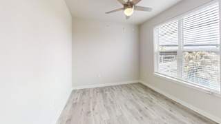 Bright bedroom with ceiling fan and large window at Bridge at Windsor Park Apartments, Austin